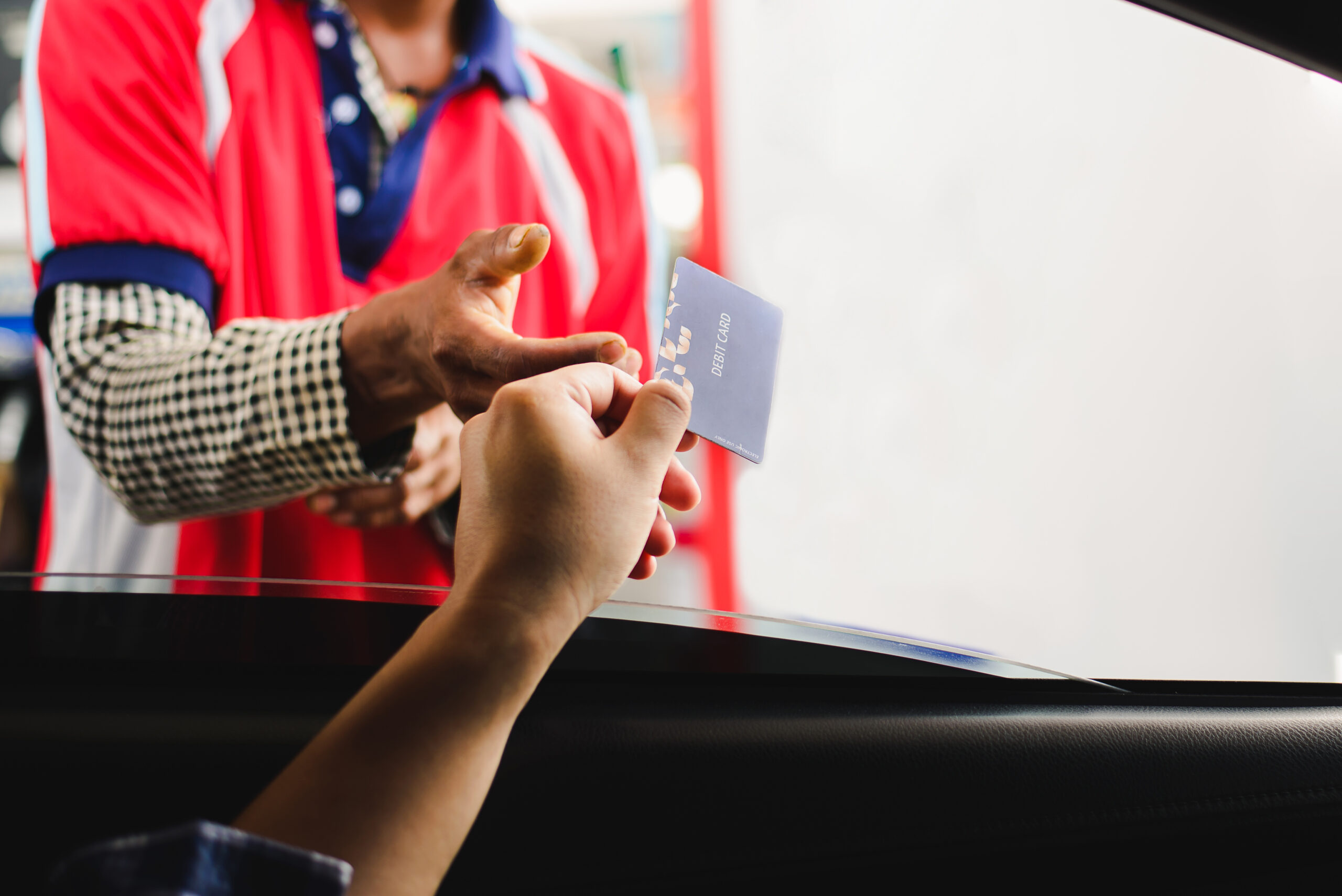 Man in a car using a debit card, young man holding payment card used to pay for gasoline, diesel, and other fuels at gas stations, Driver with fleet cards for refueling car,copy space.